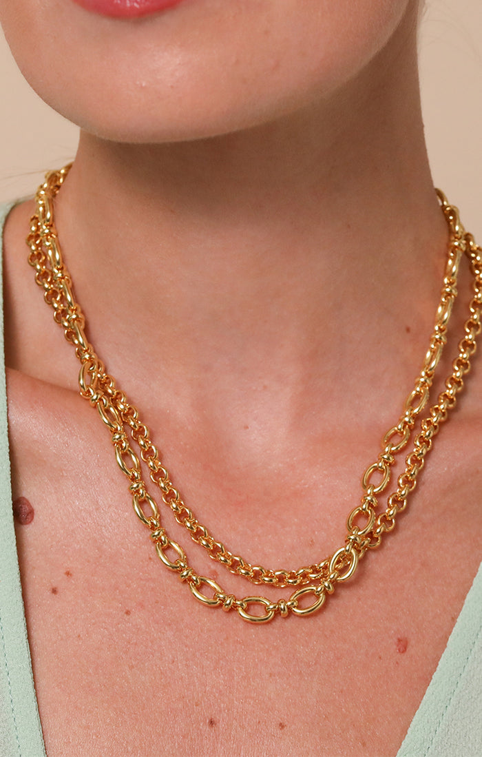 Woman wearing an elegantly layered silver snake chain and a silver long link chain necklace from Astrid & Miyu.
