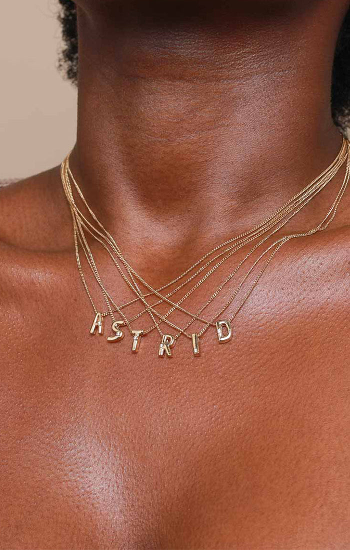 Worn shot of the Initial Pendant Necklaces with letters spelling "Astrid"